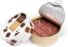 an open tin with chocolate in it on a white surface and the lid is opened