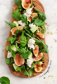 a salad with figs, cheese and greens on a wooden platter