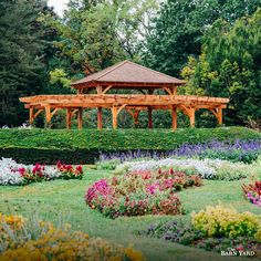 a wooden gazebo surrounded by colorful flowers and trees