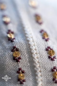 some gold and red beads on a white shirt