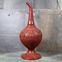 a red vase sitting on top of a stone floor