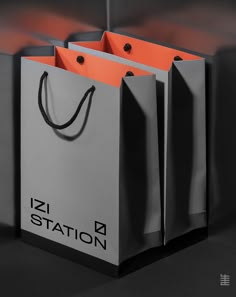 two shopping bags sitting next to each other on top of a black surface with the word zz station printed on it