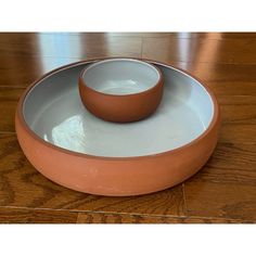 two bowls sitting on top of each other in front of a wooden table with a wood floor