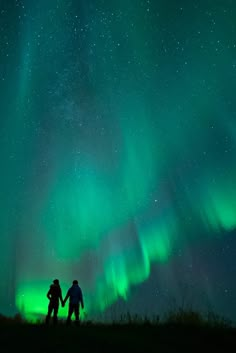 two people holding hands under the aurora lights