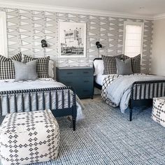 two beds in a room with black and white decor on the walls, one bed has a footstool next to it