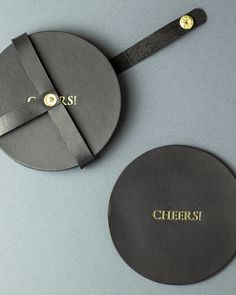 two round coasters with the word cheers engraved on them, sitting next to each other