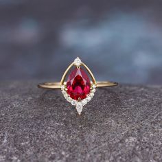 a red and white diamond ring sitting on top of a rock