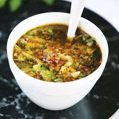 a white bowl filled with soup on top of a black plate