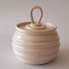 a white ceramic pot with a handle on it