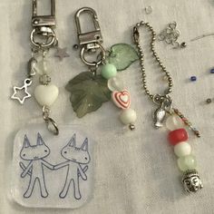 some charms are laying on top of a white cloth with beads and other items attached to them