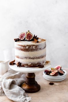 a cake sitting on top of a white plate covered in frosting and figs