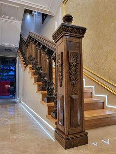 an ornate wooden stair case in a large room with beige walls and marble flooring