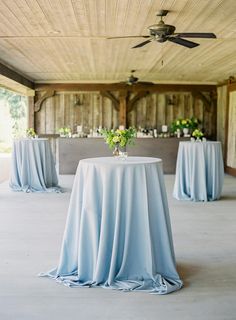 the tables are covered with blue cloths and flowers in vases on top of them