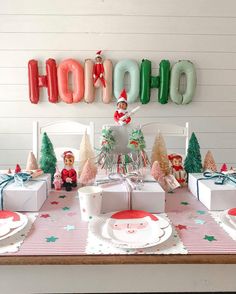 the table is set for christmas dinner with santa clause decorations and balloons on the wall