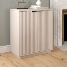 a white cabinet sitting on top of a hard wood floor next to a fire place