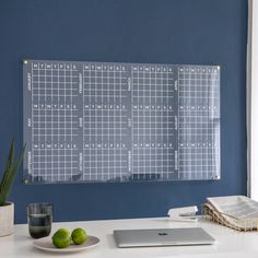 a glass magnetic calendar on a blue wall next to a plate with two limes