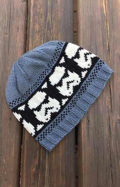 a blue and white knitted hat sitting on top of a wooden table next to a pair of scissors