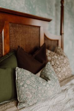 a bed with pillows on top of it and a headboard in the back ground