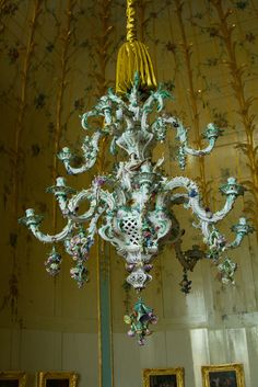 a chandelier hanging from the ceiling in a room with paintings on the walls