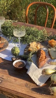 a wooden table topped with plates of food and glasses of wine next to each other