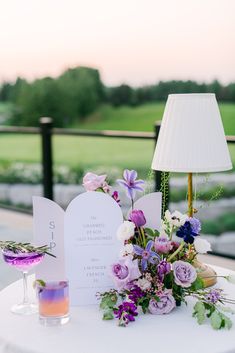 the table is set up with flowers and menus for an outdoor wedding reception at sunset