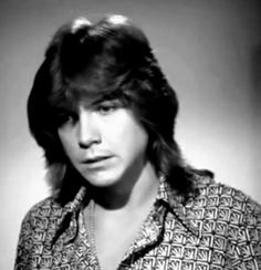 an old black and white photo of a woman with long hair wearing a patterned shirt