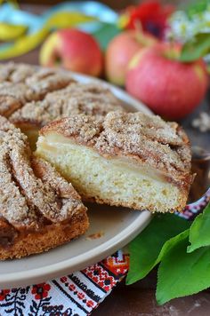 an apple pie is on a white plate next to some green leaves and apples in the background