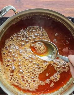 a person stirring oil in a pot with a spoon