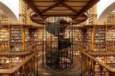 the inside of a library with many bookshelves and spiral staircases in it