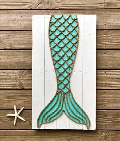 a wooden sign with a mermaid tail and starfish on it