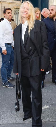 a man in a suit and tie standing on the street with other people behind him