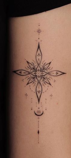 a cross tattoo on the side of a woman's stomach, with an intricate design