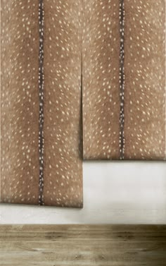 two brown curtains with white spots on them in front of a wooden floor and wall