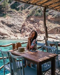 a woman sitting at a table with a cake in front of her on the beach