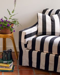 a black and white striped couch next to a potted plant