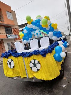 a car decorated with balloons and decorations for a soccer themed event in the middle of town