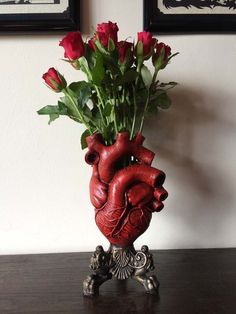 a vase filled with roses sitting on top of a table next to two framed pictures