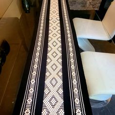 a black and white table runner sitting on top of a glass table next to two chairs