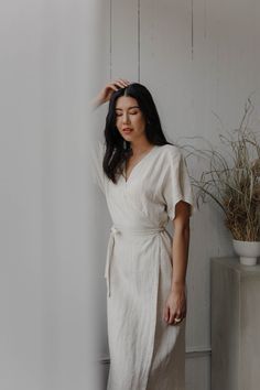 "This carefully tailored lightweight wrap dress has a cocktail length, roomy short sleeves, a cinched waist and an A-line skirt. It also has back darts, a built in wrap belt and invisible pockets. We used the highest quality linen sourced in Canada which is breathable, soft and pre washed with an antique finish. Like all of our pieces, this dress is handmade by us to order in our studio in British Columbia. Please provide us with your measurements so we can ensure the perfect fit. If you have an Dress Capsule Wardrobe, Casual Wedding Guest Dress, Wrap Dress Outfit, Casual Wedding Guest, Casual Wedding Guest Dresses, Long Wrap Dress, Wrap Dress Pattern, Linen Wrap Dress, White Linen Dresses