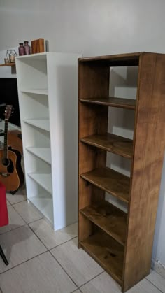 a wooden book shelf sitting next to a red chair in front of a white wall