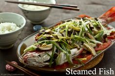 a plate with rice and vegetables on it next to two bowls filled with rice, chopsticks and sauce