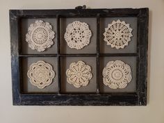 six crocheted doily are arranged in a shadow box on the wall,