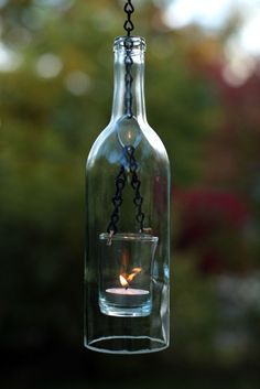 a candle in a glass bottle hanging from a chain