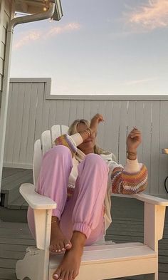 a woman sitting in a white chair on top of a porch