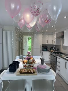 balloons are hanging from the ceiling above a table with plates and cups on it in a kitchen