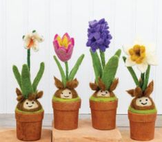 four potted plants with flowers in them sitting on wooden blocks next to each other