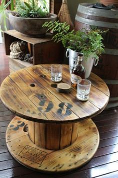 a wooden table with two glasses on it and some plants in the backround