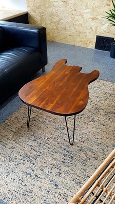 a wooden table sitting on top of a blue rug in a living room next to a black couch