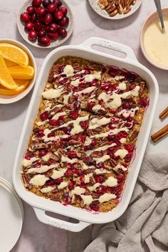 a casserole dish with cranberries, oranges and pecans on the side