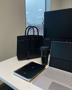 an open laptop computer sitting on top of a white desk next to a black bag